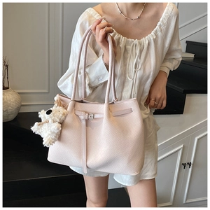 Detail of light beige tote bag with woven texture and a cute white plush bear pendant