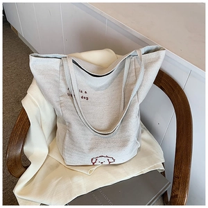 Detailed close-up of grey herringbone canvas tote bag with red dog embroidery