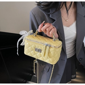 Close-up of lemon yellow quilted crossbody bag with pearl charms and chain handle