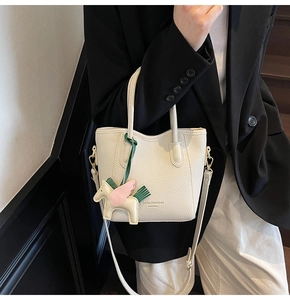 Close-up of white lychee leather texture and golden brand logo on a stylish bucket bag