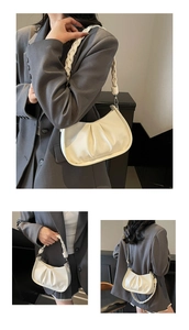 Detail of off-white pleated shoulder bag featuring woven handle and adjustable strap