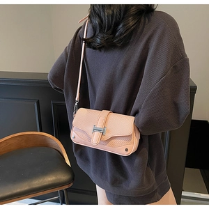 Close-up of pink woven crossbody bag featuring a silver metal H-buckle and leather strap