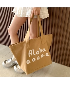 Close-up of canvas tote bag featuring white Aloha lettering on camel brown fabric