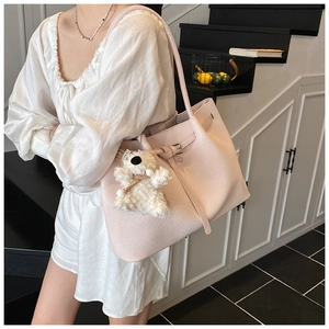 Detailed shot of pink woven texture tote bag with buckle and plush bear charm