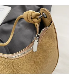 Dettaglio di una borsa gialla con cerniera in metallo liscia e pelle martellata