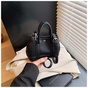 Close-up of black lychee texture mini handbag with silver rivet and leather strap