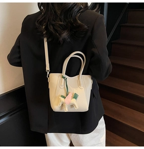 Detail view of cream lychee texture bucket bag with Pegasus charm on a leather strap