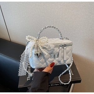 Detailed view of light blue quilted mini bag with pearl bow and silver heart charm