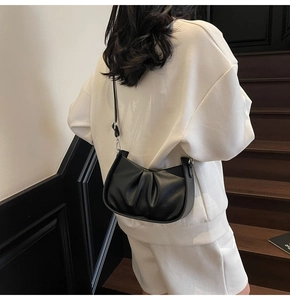 Detail view of black lychee texture pleated cloud bag worn as a shoulder bag
