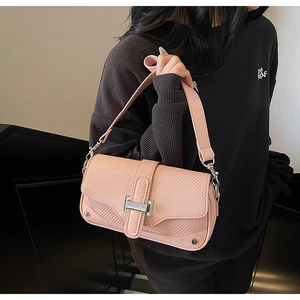 Close-up of pink woven crossbody bag with silver H-shaped buckle and metal studs detail