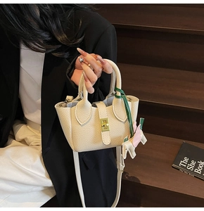 Détail du sac seau en cuir beige grainé avec fermoir doré et breloque cheval