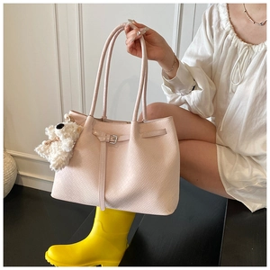 Detail view of pink woven leather tote bag with a white teddy bear charm accessory