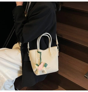 Detail of lychee pattern leather bucket bag in beige with a decorative pegasus pendant