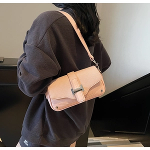 Detail of pink animal pattern crossbody bag with silver H-buckle on grey sweater