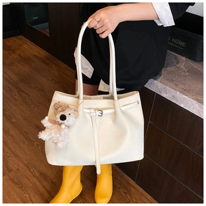 Detail of white woven texture tote bag with minimalist strap and plush dog charm