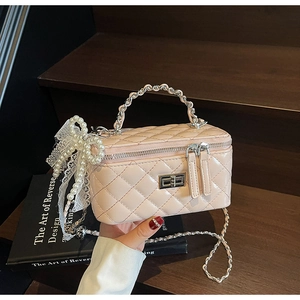 Detail of pink quilted vanity bag featuring silver clasp and pearl bow charm