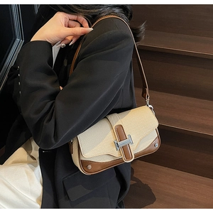 Detail of contrast stitching, woven fabric texture and silver H-buckle on a small square bag
