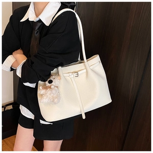 Detail showing white textured tote bag with a decorative strap and cute puppy pendant