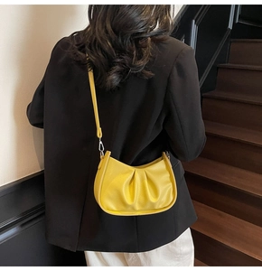 Detail of bright yellow ruched shoulder bag with textured leather and silver hardware