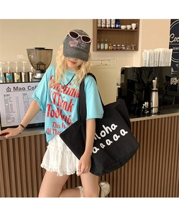 Close-up of black canvas tote bag with white lettering for casual summer outfit