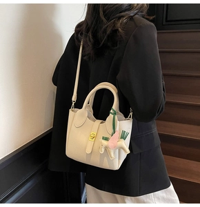 Détail du sac seau beige à motif litchi avec fermoir doré et charm petit poney élégant