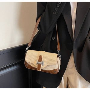 Detail of contrast stitching, woven texture and silver metal buckle on a shoulder bag