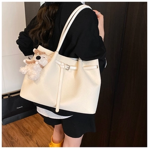 Detail of white tote bag with leather texture, thin strap buckle and plush dog charm