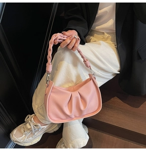 Detail of pink pleated leather handbag featuring a chic woven handle and silver metal hardware