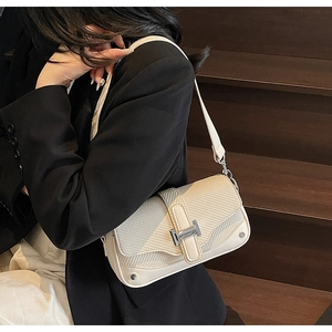 Detail view of cream crossbody bag featuring woven texture and silver H-buckle hardware