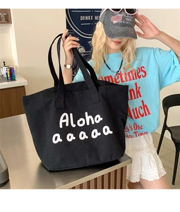 Detail of a large black canvas tote bag with white cartoon print worn by a model