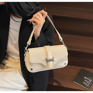 Detail view of woven flap texture and silver H-buckle on cream shoulder bag