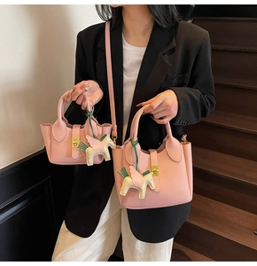 Vue détaillée de sacs seau roses à motif de litchi avec breloques pégase en cuir