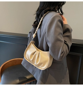 Detail of pleated beige underarm bag with woven shoulder strap and soft leather texture