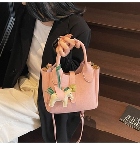 Détail du sac seau rose en cuir grainé avec fermoir rotatif et breloque petit poney