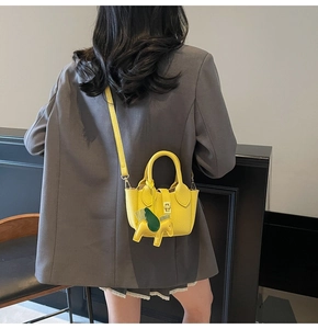 Sac seau jaune à motif litchi avec breloque cheval sur une veste de costume grise