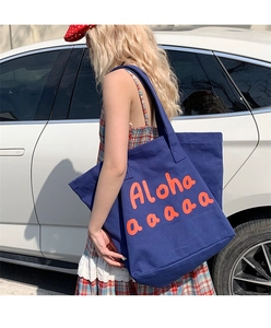 Detail shot of the durable blue canvas tote bag showing the orange Aloha printed text