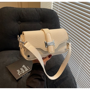 Detail of minimalist cream crossbody bag featuring textured woven flap and silver metal buckle