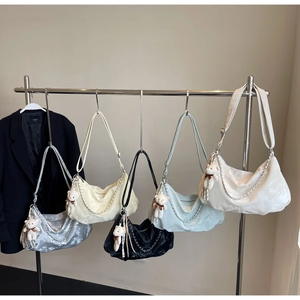 Détail de sacs croissants en cinq couleurs avec chaîne argentée et breloque ourson