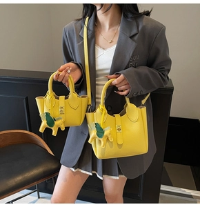 Détail de sacs seaux en cuir grainé jaune en tailles moyenne et petite avec charme de cheval