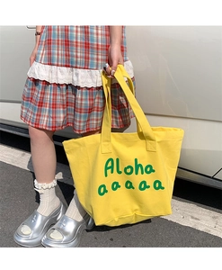 Detail of yellow canvas tote bag with green Aloha print and sturdy shoulder straps