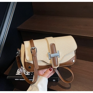 Detail of a contrast woven shoulder bag with brown leather trim and silver metal buckle