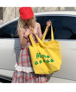 Detail of high-capacity yellow canvas tote bag with green Aloha print and sturdy handles