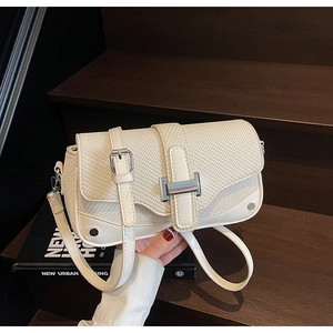 Close-up of woven flap texture and silver H-buckle on minimalist crossbody bag