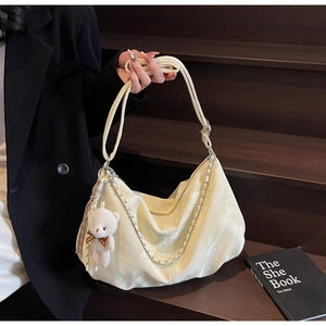 Détail du sac hobo crème avec chaîne argentée, cuir souple et breloque ours en peluche