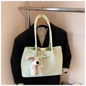 Detail of light green tote bag featuring leather texture and cute plush bear charm