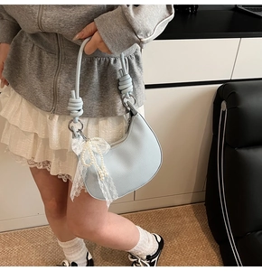 Dettaglio borsa hobo azzurra trama litchi con ciondolo di pizzo perla e tracolla annodata