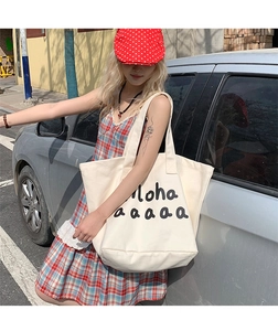 Detail of canvas tote bag with Aloha print styled with retro summer dress and hat