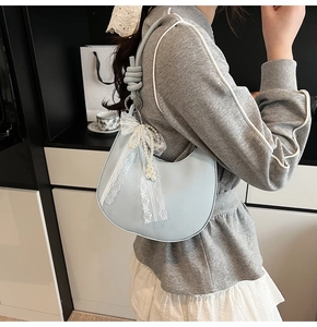 Dettaglio borsa a mezzaluna celeste con texture litchi e fiocco di pizzo e perle