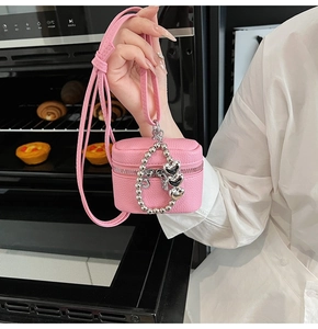 Detailed macro view of pink litchi grain leather mini bag with silver heart chain
