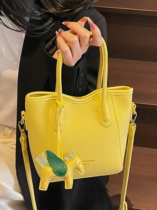 Bright yellow lychee leather bucket bag with horse charm and dual carry handles
